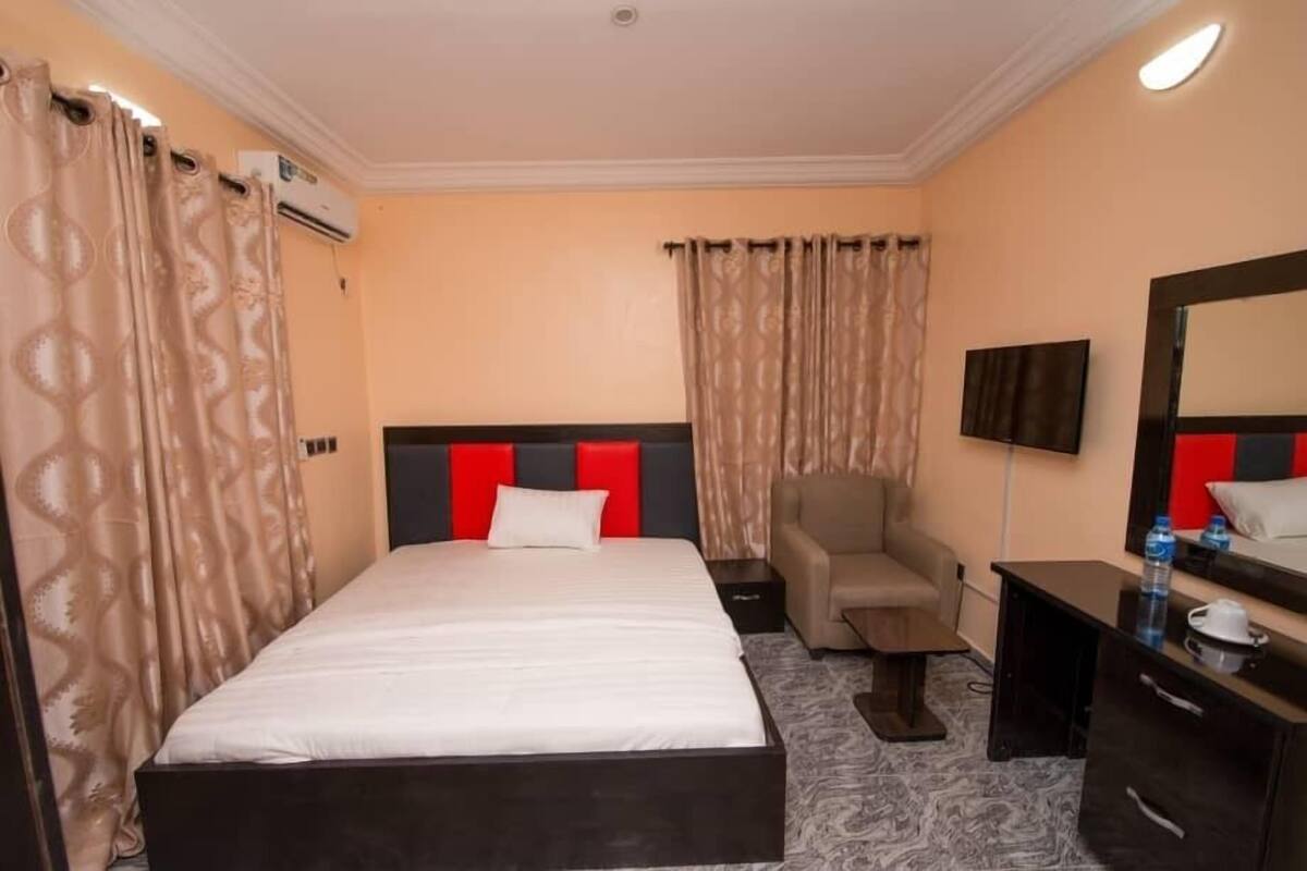 Une chambre d’hôtel équipée d’un lit, d’une chaise, d’un bureau, d’un miroir et d’un appareil de climatisation.