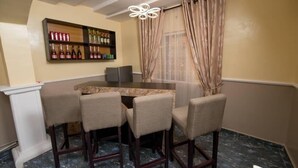 Un comedor con una mesa redonda, cuatro sillas, una vinoteca con botellas y una araña.