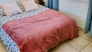 A bedroom with a bed, a nightstand, a window with curtains, and wall decorations.