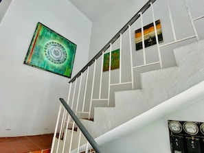 Staircase leads to an upper level, flanked by three framed artworks.
