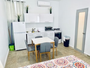 Compact kitchen with a sink, microwave, and stove, plus a dining table and chairs.