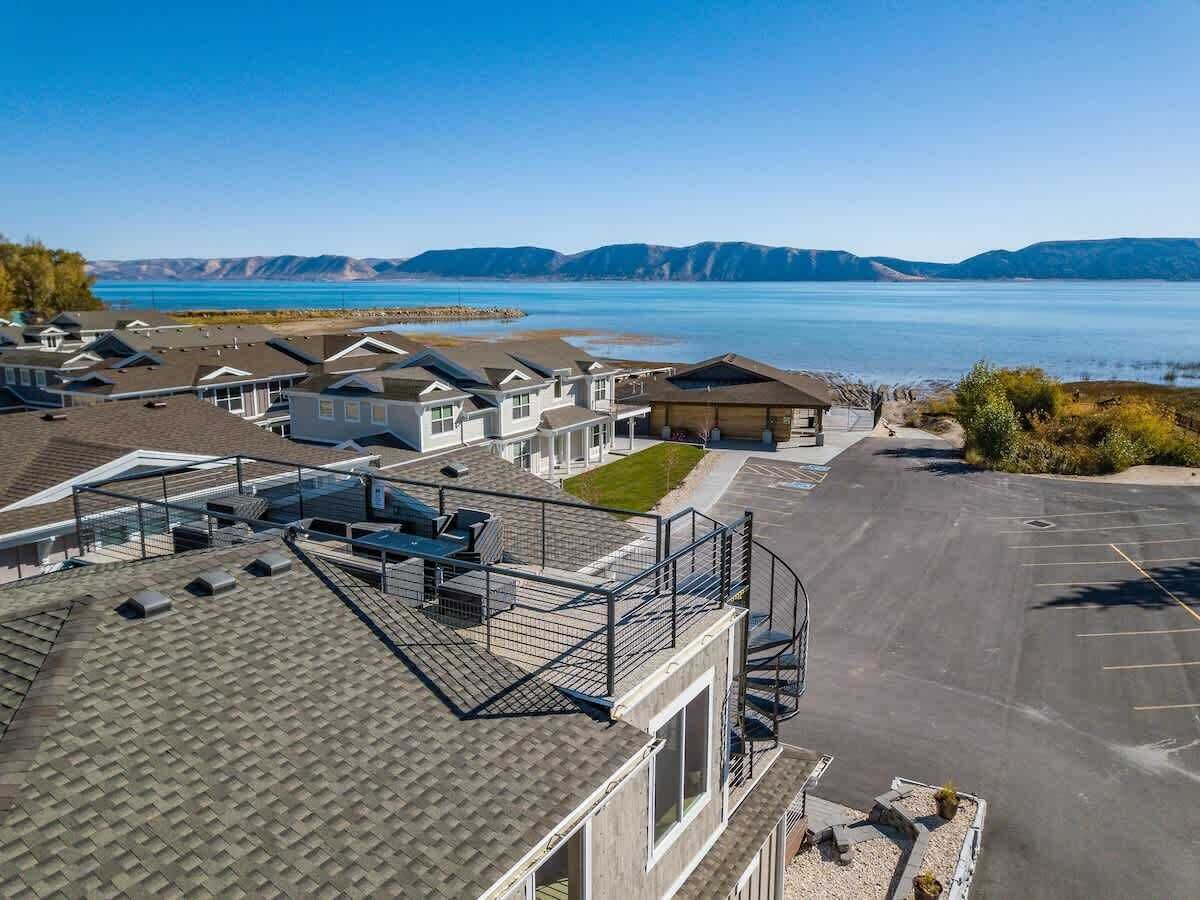 A residential area with multiple houses, a parking lot, and a body of water in the background.