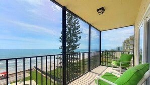A balcony with a view of the beach and ocean, equipped with a pool, green chairs, and a railing. - Breathtaking Views from this 5th floor Ocean Front Condo  (Satellite Beach)