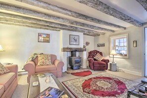 A cozy living room with a fireplace, two sofas, a red rug, and a wooden ceiling.