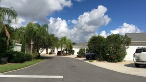 Una calle residencial con casas, automóviles estacionados y abundante vegetación.