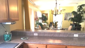 Una cocina con armarios de madera, una encimera y una zona de comedor con una mesa y sillas.