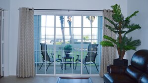 Ein Wohnzimmer mit einer Schiebeglastür, die auf einen Balkon mit Gartenmöbeln führt.