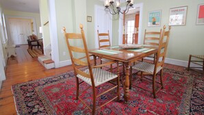 A dining area with a wooden table, four chairs, and a red patterned rug.