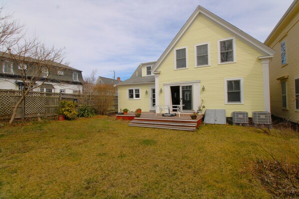A two-story house with a front porch, a small yard, and a wooden fence.