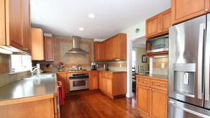 A kitchen with wooden cabinets, stainless steel appliances, and a tiled backsplash.