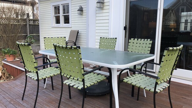 A patio with a table and chairs, a potted plant, and a wooden deck.