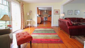 A living room with a red sofa, a wooden floor, and a colorful striped rug.