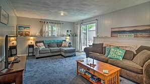 A cozy living room with a sectional sofa, a coffee table, and a television. - Walk to Haigis Beach: Cape Cod Retreat w/ Deck! (Dennis)