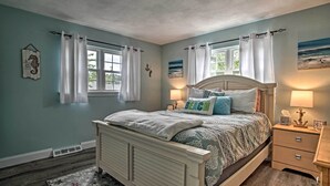 A bedroom with a bed, nightstands, and a window with curtains. - Walk to Haigis Beach: Cape Cod Retreat w/ Deck! (Dennis)