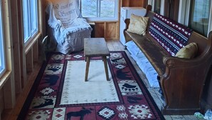 L’intérieur d’un chalet accueillant, avec un plafond en bois, un canapé, un banc et un tapis orné de motifs animaliers.