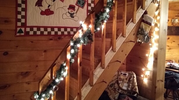 Un escalier en bois décoré de guirlandes et d’une courtepointe représentant des bonhommes de neige et un sapin de Noël.