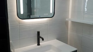 A bathroom with a white sink, black faucet, and a mirror with illuminated edges. - Maleni stan (Zagreb)