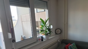 A living room with a window, radiator, and a clock on the wall. - Maleni stan (Zagreb)