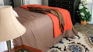 A bedroom with a bed, a dresser, a television, and a ceiling fan.
