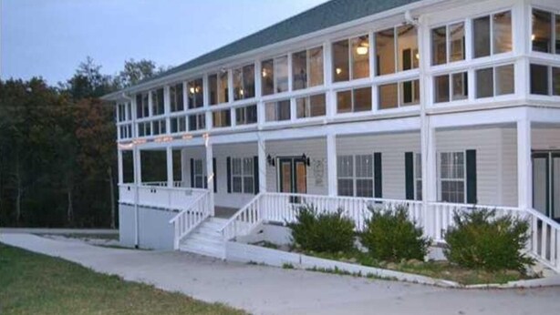A two-story building with a covered porch and a staircase leading to the entrance.