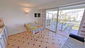Ein Essbereich mit Tisch für vier Personen, eine Küche mit Schränken und Herd sowie ein Balkon mit Stühlen und Tisch.