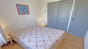 Ein Schlafzimmer mit einem Bett, einem Nachttisch, einer Lampe, einer Tür und einem Wandbild.
