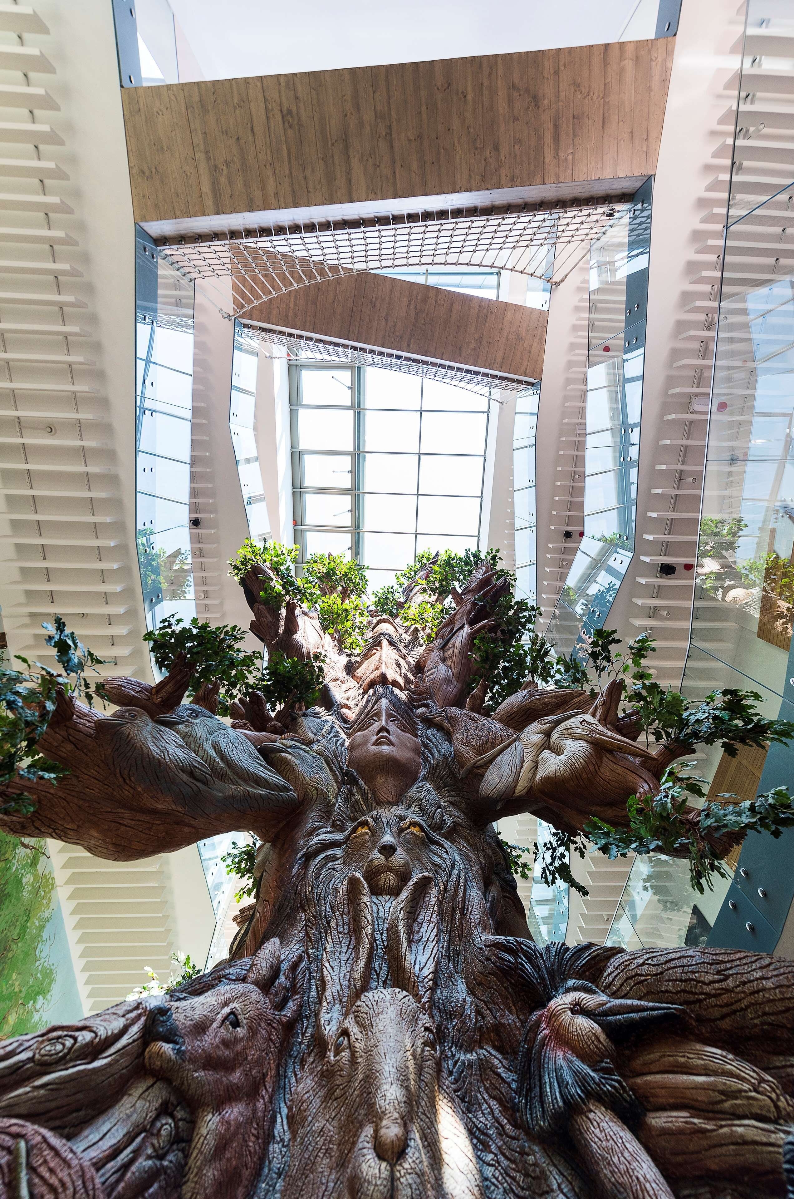 Una gran escultura interior que recuerda a un árbol con múltiples ramas y hojas.
