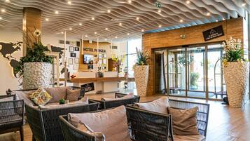 A hotel lobby with wicker furniture, a reception desk, and a modern ceiling design.