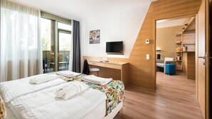 Habitación de hotel con cama, escritorio, televisión y baño visible a través de una puerta abierta.