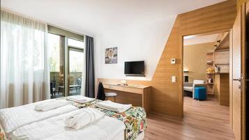 A hotel room with a bed, a desk, a television, and a bathroom visible through an open door.