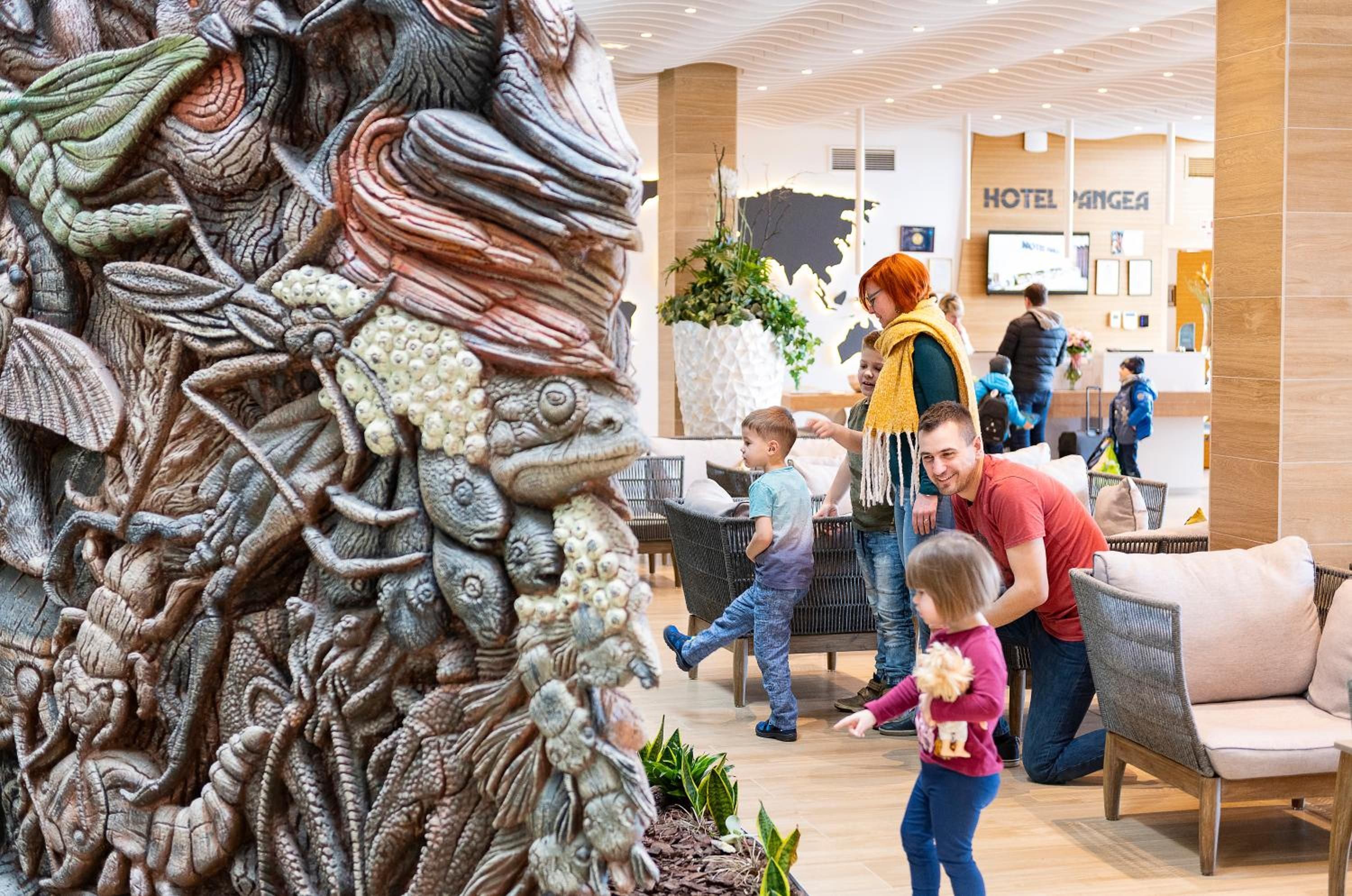 Un hall de hotel con una gran escultura elaborada, zonas de estar y un mostrador de recepción.
