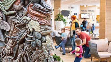 Un hall de hotel con una gran escultura elaborada, zonas de estar y un mostrador de recepción.