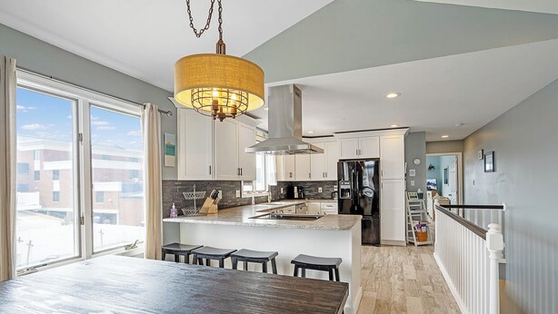 A modern kitchen with a central island, white cabinetry, and a large window providing a view of the outside. - Renovated with Backyard Oasis! Quick Walk to Town & Beach. 4 BRs. Sleeps 10 (Sea Isle City)
