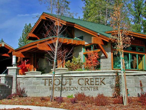 A lodge with a stone facade, wooden beams, and a sign reading "Trout Creek Recreation Center".