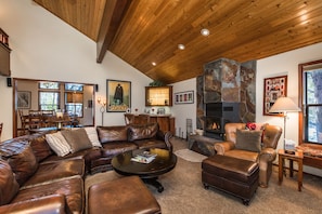 A cozy living room with a leather sectional sofa, a fireplace, and a dining area visible through a glass door.