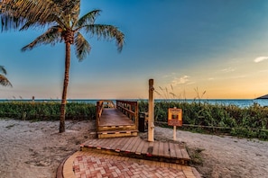 A wooden boardwalk leading to a beach with a warning sign about sea turtles.