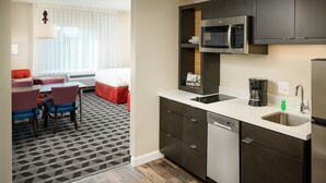A compact kitchen with a microwave, sink, and dishwasher. There is a dining area with a table and chairs.