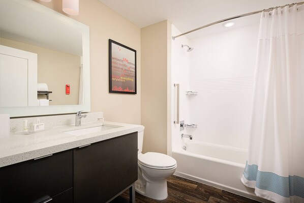 A modern bathroom with a white bathtub, a toilet, and a vanity with a mirror.
