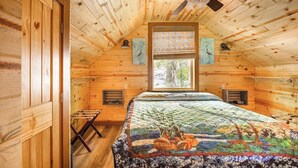 A wooden cabin bedroom with a bed, a ceiling fan, and a window with blinds. - Blue Heron Treehouse - Private Hot Tub (Guild)