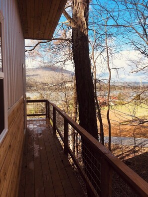 A wooden deck with a railing, overlooking a landscape with trees and distant hills. - Blue Heron Treehouse - Private Hot Tub (Guild)
