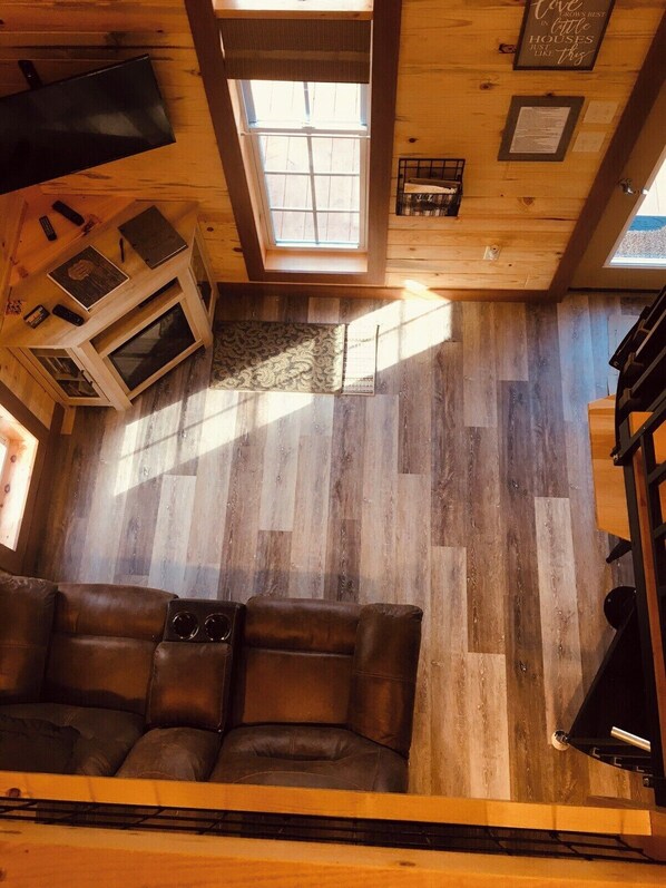 A cozy cabin interior with a wooden floor, a sofa, a small table, and a window.