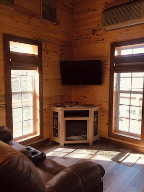A cozy room with a wooden interior, a flat-screen TV mounted on the wall, and a built-in entertainment unit.
