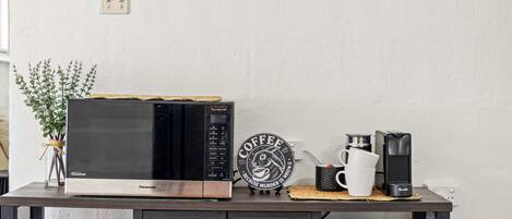 A kitchen counter with a microwave, coffee maker, and a decorative sign.