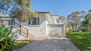 A modern two-story house with a gravel driveway, a wooden staircase, and a garage. - Kings Beach Home Amongst Tranquil Gardens (Kings Beach)