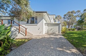 A modern two-story house with a gravel driveway, a wooden staircase, and a garage. - Kings Beach Home Amongst Tranquil Gardens (Kings Beach)