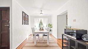 A modern kitchen with a dining area, wooden flooring, and a built-in TV. - Kings Beach Home Amongst Tranquil Gardens (Kings Beach)