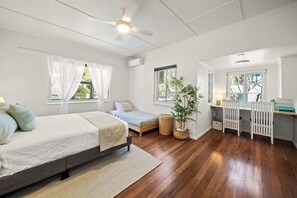 Een slaapkamer met een bed, een bureau en een raam.