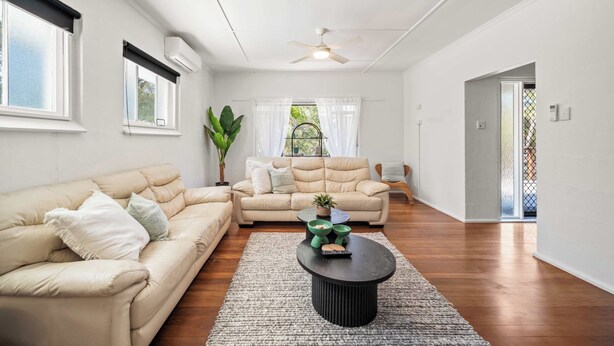 A spacious living room with a beige sofa, a round coffee table, and a ceiling fan. - Kings Beach Home Amongst Tranquil Gardens (Kings Beach)