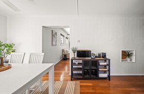 Een moderne woonkamer met een eethoek, houten vloeren en een koffiehoek.