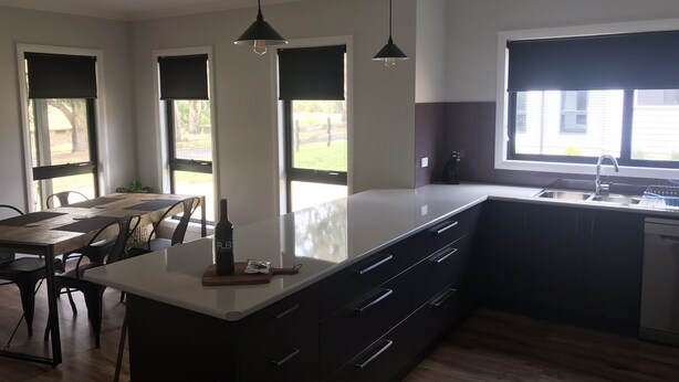 A modern kitchen with a large island, dark cabinetry, and pendant lighting. - Bright Racecourse View #2 (Bright)